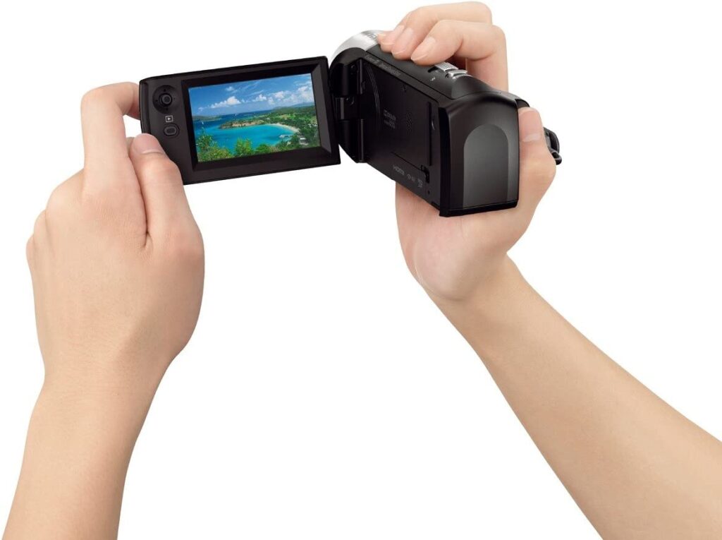 Person holding a Sony Handycam HDR-CX405 video camera with LCD screen on white background, Sony - HDRCX405