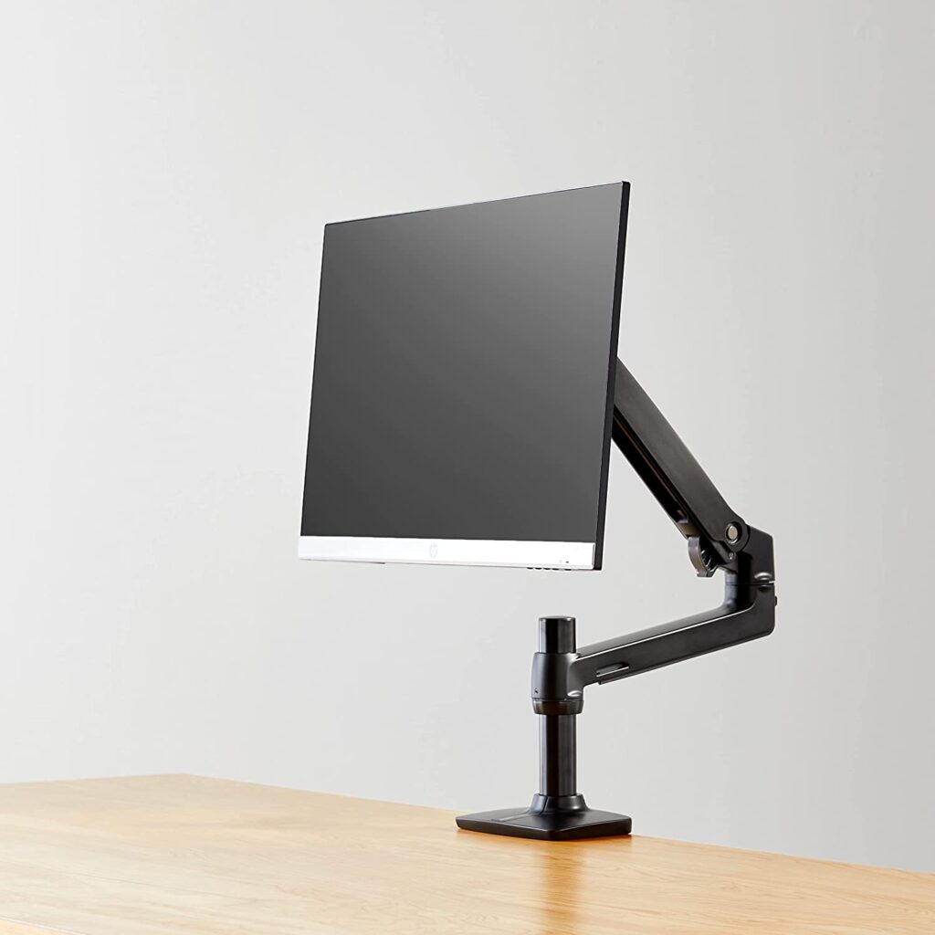 A computer monitor sitting on a wooden desk. The monitor is attached to a dual display mount arm. - productcruise.com
