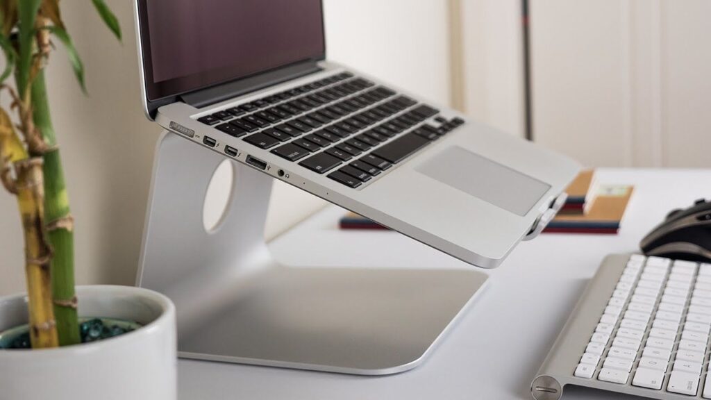 Laptop sitting on a stand next to a keyboard and a plant on a desk, Rain Design mStand